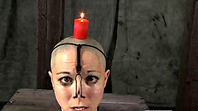 Candle drips wax on the head of a bound girl